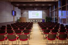 Soba pripravljena za predavanja ali konferenco, z veliko stoli, usmerjenimi proti projekcijskemu platnu.