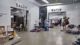 Notranjost prodajnega prostora z dvema vhodoma – na levi strani salon s pohištvom, na desni butik z oblačili; med prostoroma so razstavljeni izdelki in lutke z oblačili.